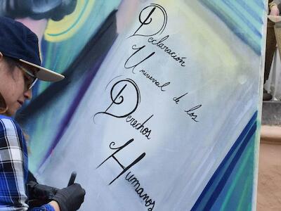 Foto de UN Colombia/Jose Rios.  Un artista de grafitis en Colombia crea una imagen sobre la declaración de los derechos humanos.