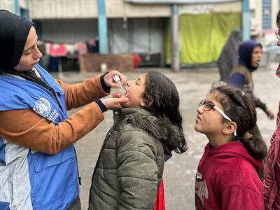 © UNRWA/Mohammed Hinnawi En febrero de 2025, unos niños de Gaza reciben la vacuna contra la poliomielitis de manos de un trabajador de la ONU.