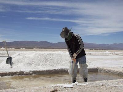 Con todo su cuerpo cubierto y los pies sumergidos en las piletas de salmuera, un operario trabaja con el viejo método de la pala y la piqueta en Salinas Grandes en Argentina. Foto:Rodolfo Chisleanschi.