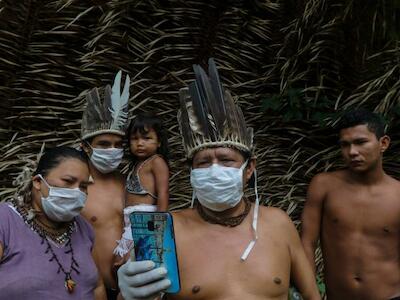 - Indígenas recibiendo orientación médica a través de un celular, en medio de la pandemia del covid-19, en la comunidad sahu-ape, Amazonas (Brasil).  Foto: RICARDO OLIVEIRA. AFP
