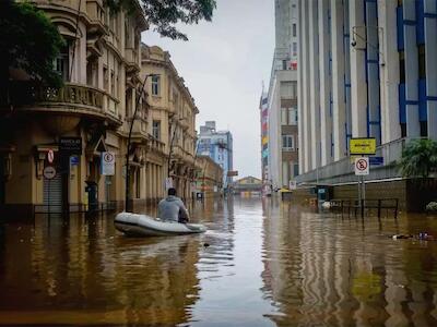 Un hombre recorre con un bote inflable las calles inundadas por fuertes lluvias en Porto Alegre, sur de Brasil, mientras que en el norte del país los ríos se reducían a mínimos históricos debido a una sequía sin precedentes. Imagen: Dialogue Earth