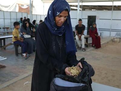 Samah Hamdan, una mujer que ha sido desplazada, recoge algo de pasta para ella y su familia. Foto de Médico Sin Fronteras.