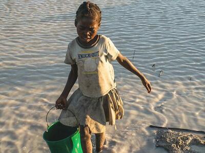 Foto: OCHA/Viviane Rakotoarivony. Un niño carga agua recogida en un estanque artificial en el centro de Madagascar.
