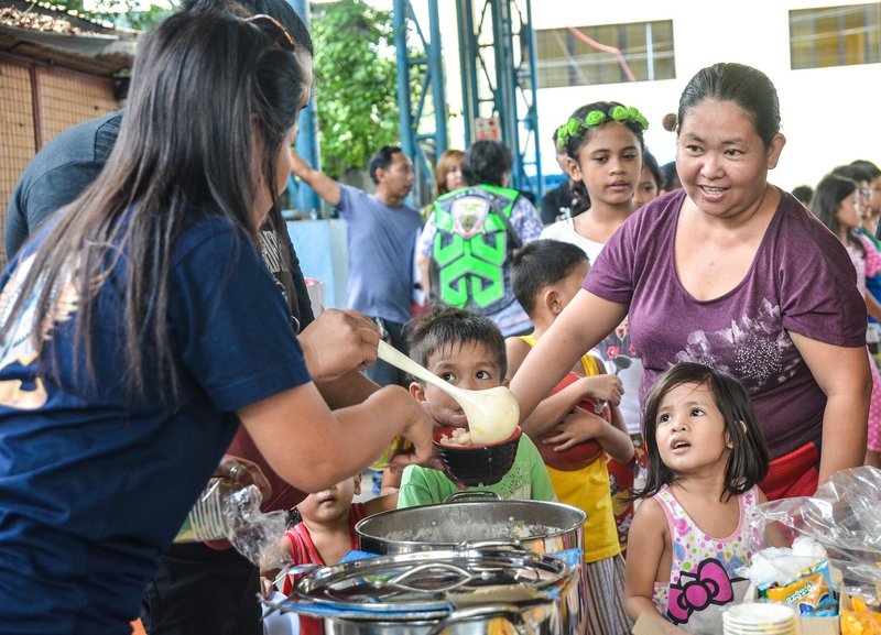 Ciudad de Quezón, Filipinas. 28 de julio de 2018. Niños y niñas haciendo cola durante un acto de servicio comunitario del programa de alimentación. Alamy