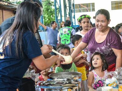 Ciudad de Quezón, Filipinas. 28 de julio de 2018. Niños y niñas haciendo cola durante un acto de servicio comunitario del programa de alimentación. Alamy