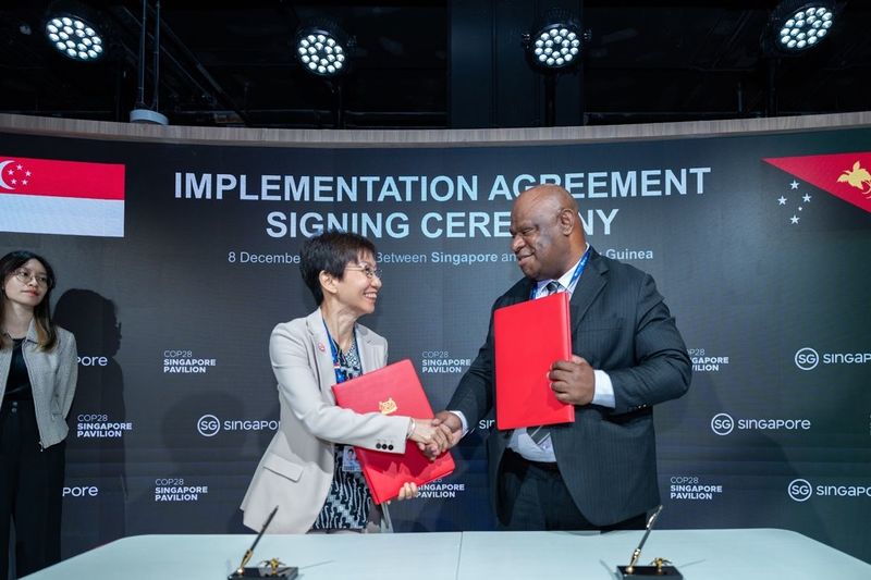 Grace Fu, Ministra de Sostenibilidad y Medio Ambiente de Singapur, estrechando la mano del Ministro de Medio Ambiente, Conservación y Cambio Climático de Papúa Nueva Guinea, Simo Kilepa, para sellar su primer Acuerdo de Implementación de Créditos de Carbono, un marco que permite a ambos países transferir créditos de carbono. Diciembre de 2023. LinkedIn Grace Fu